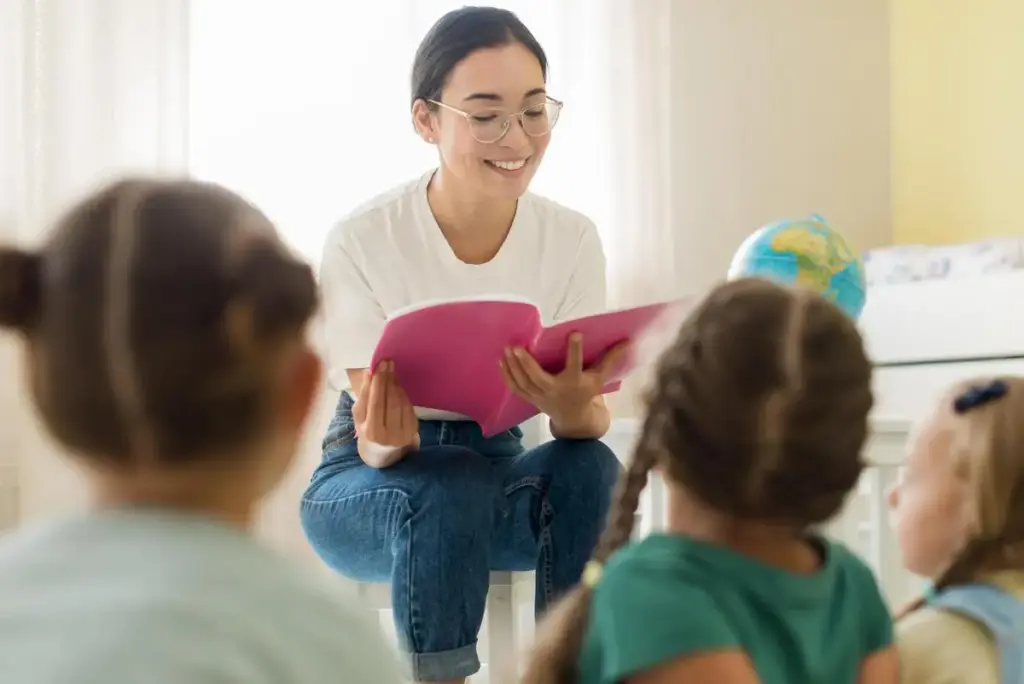 Uma mulher lendo para crianças em uma sala de aula.

