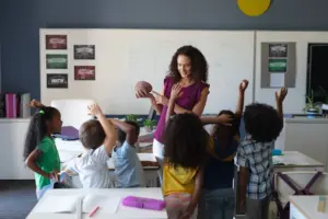 professora da educação básica em sala de aula com alunos fazendo perguntas concurso see mg