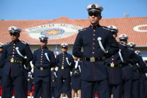 Imagem de uma cerimônia militar da Polícia Militar do Estado de São Paulo (PM SP), com oficiais em uniforme de gala azul-marinho e branco, em formação disciplinada sob um céu claro. - Concurso PM SP Oficial