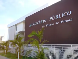 Fachada marrom com placa metálica escrito Ministério Público do Estado do Paraná. Liberado consulta aos locais de horário de prova.