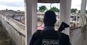 Agente penitenciário da Polícia Penal BA em pé na entrada do presídio, na guarita.