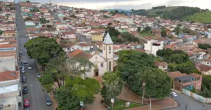 Vista panorâmica da cidade de Bandeira do Sul, Minas Gerais, mostrando a praça central rodeada por árvores.