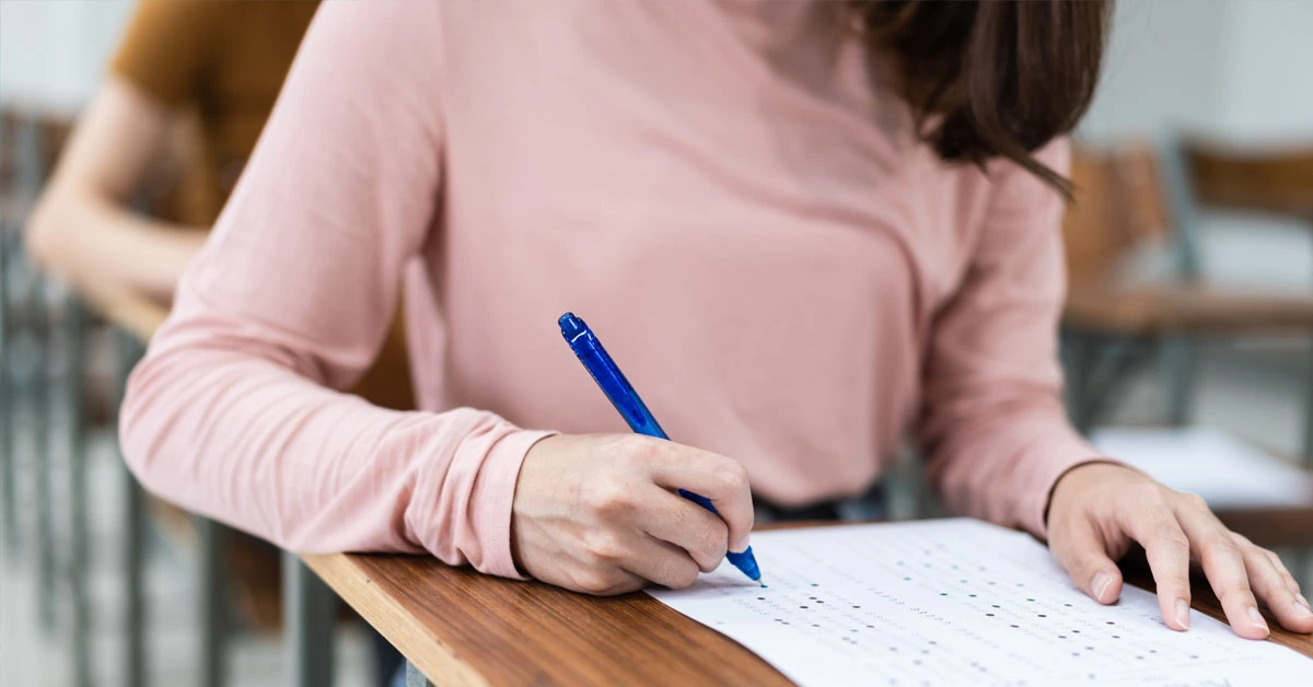 Mulher jovem escrevendo em uma folha de papel enquanto está sentada em uma mesa de estudo / Codevasf