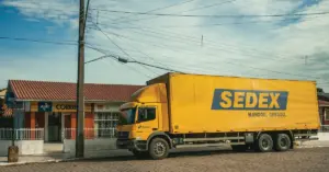 Caminhão amarelo do SEDEX dos Correios estacionado em frente a uma das agências do órgão