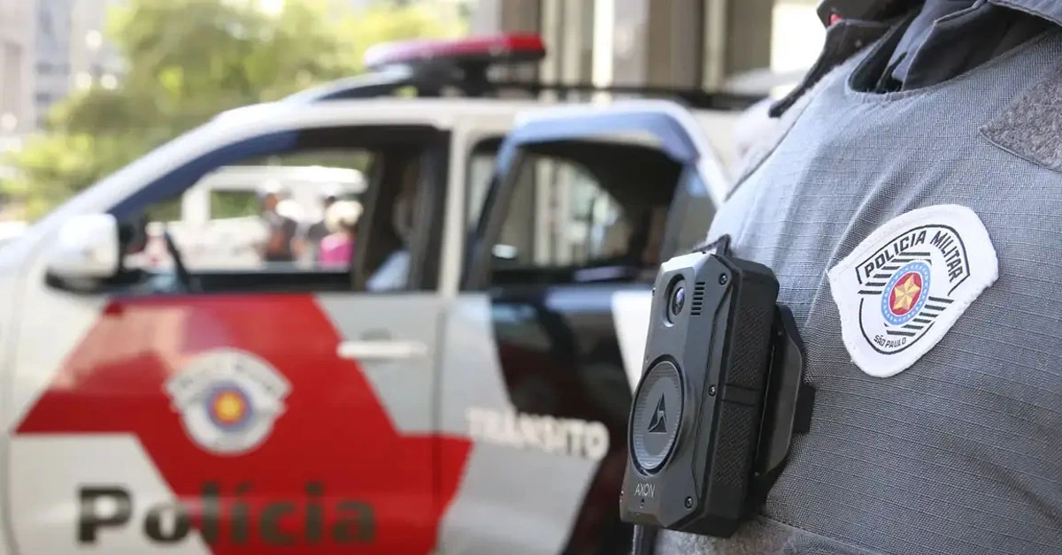 Viatura da Polícia Militar de São Paulo estacionado na rua e unifome policial em primeiro plano /PM SP