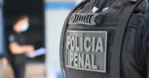 Policial penal de costas utilizando colete preto com escrita Polícia Penal / Concurso Polícia Penal RJ