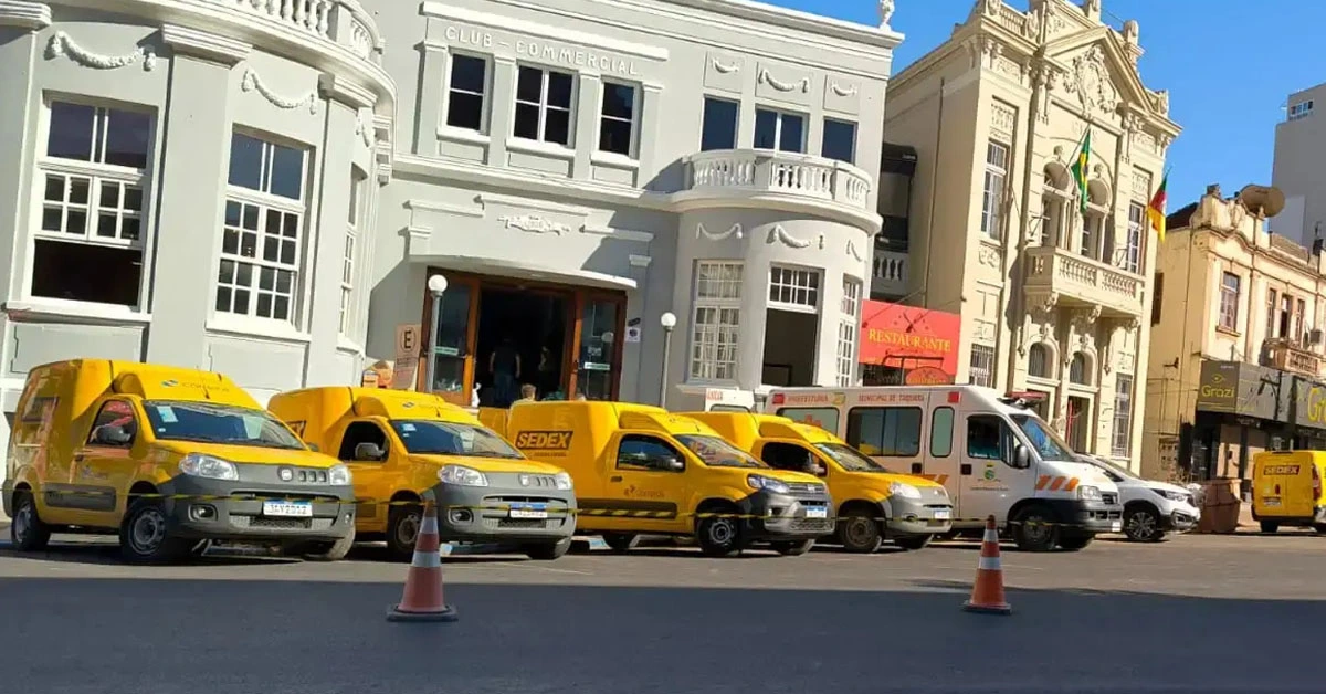 Um grupo de vans amarelas do Sedex estacionadas em frente a um prédio / Concurso Correios