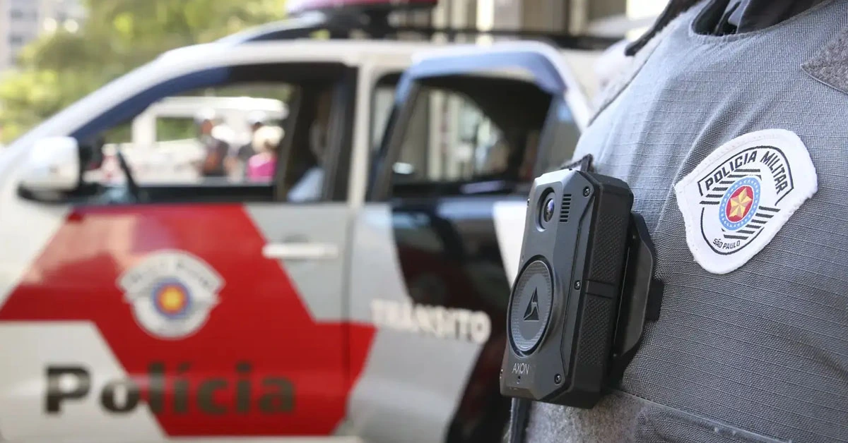 Viatura da Polícia Militar de São Paulo estacionado na rua e unifome policial em primeiro plano / Edital PM SP