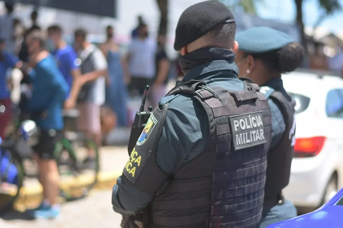 Policial militar aprovado no concurso PM SE de costas, fardado, em um dia ensolarado.