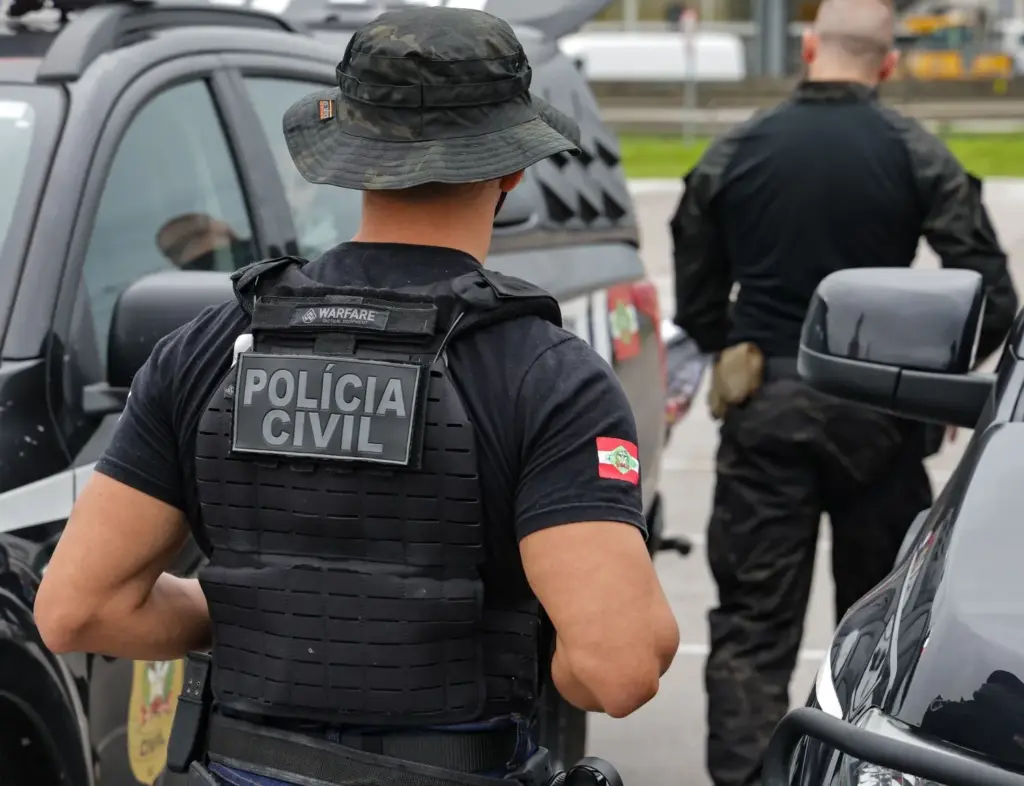 agente de policia do concurso pc sc usando farda de costas 