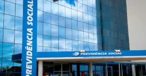 Entrada do INSS com um prédio azul espelhado atrás / Concurso INSS