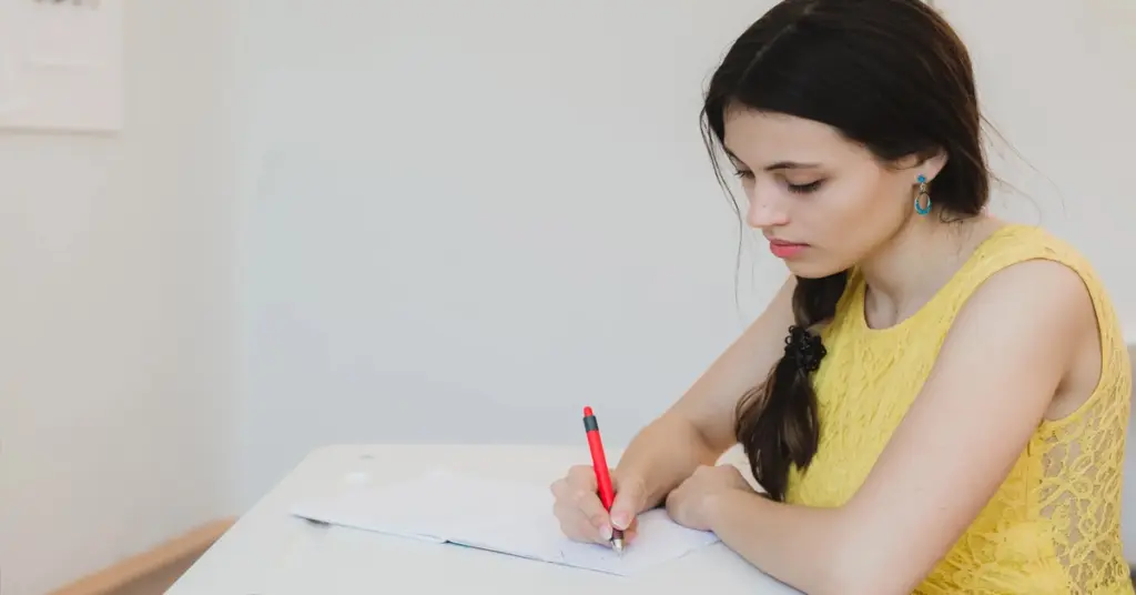 Mulher estudando para concursos públicos com caneta na mão.