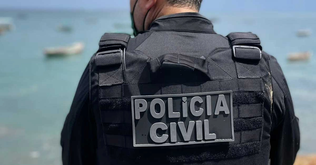 Policial civil de costas, usando colete tático preto com identificação "Polícia Civil" / Concurso PC BA