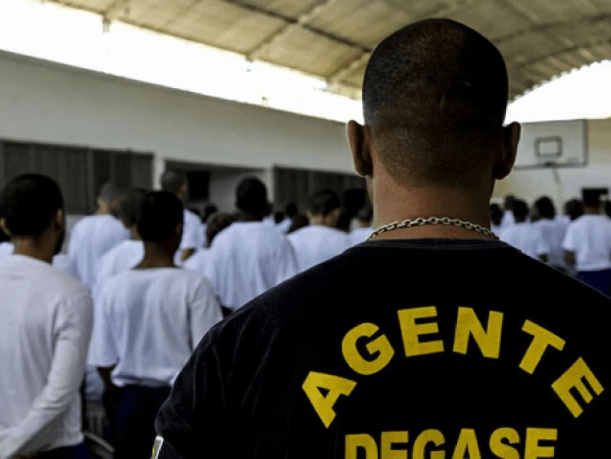 Um agente DEGASE juntamente com internos no pátio