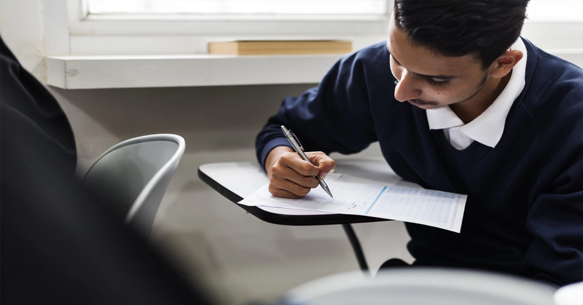 Estudante sentado escrevendo em papel / Concurso Seplan SE