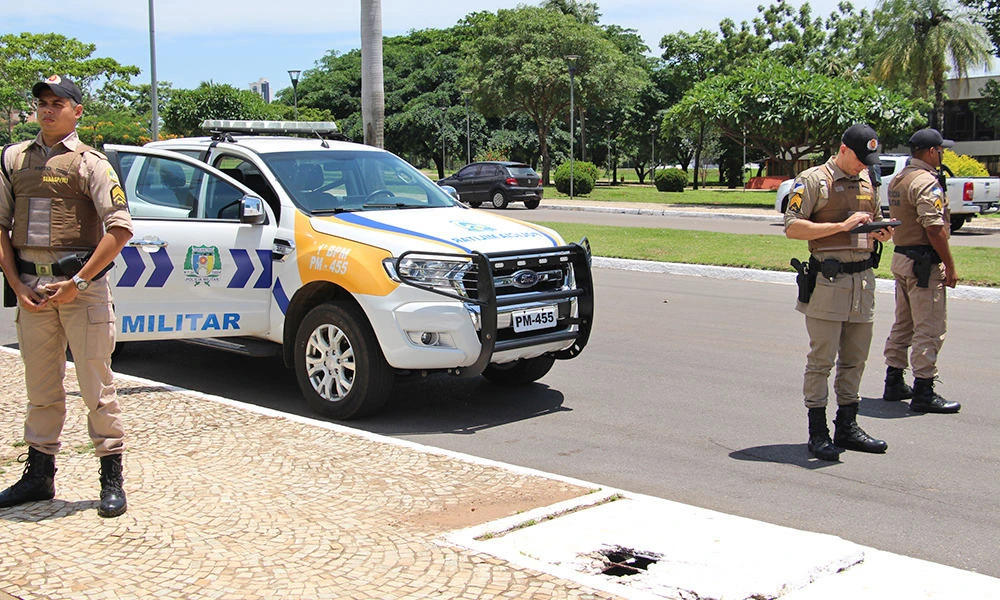 Três policiais aprovados no concurso PM TO trabalhando perto da sua viatura.