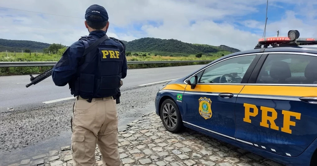 Polícial Rodoviário Federal ao lado do carro / Concurso PRF