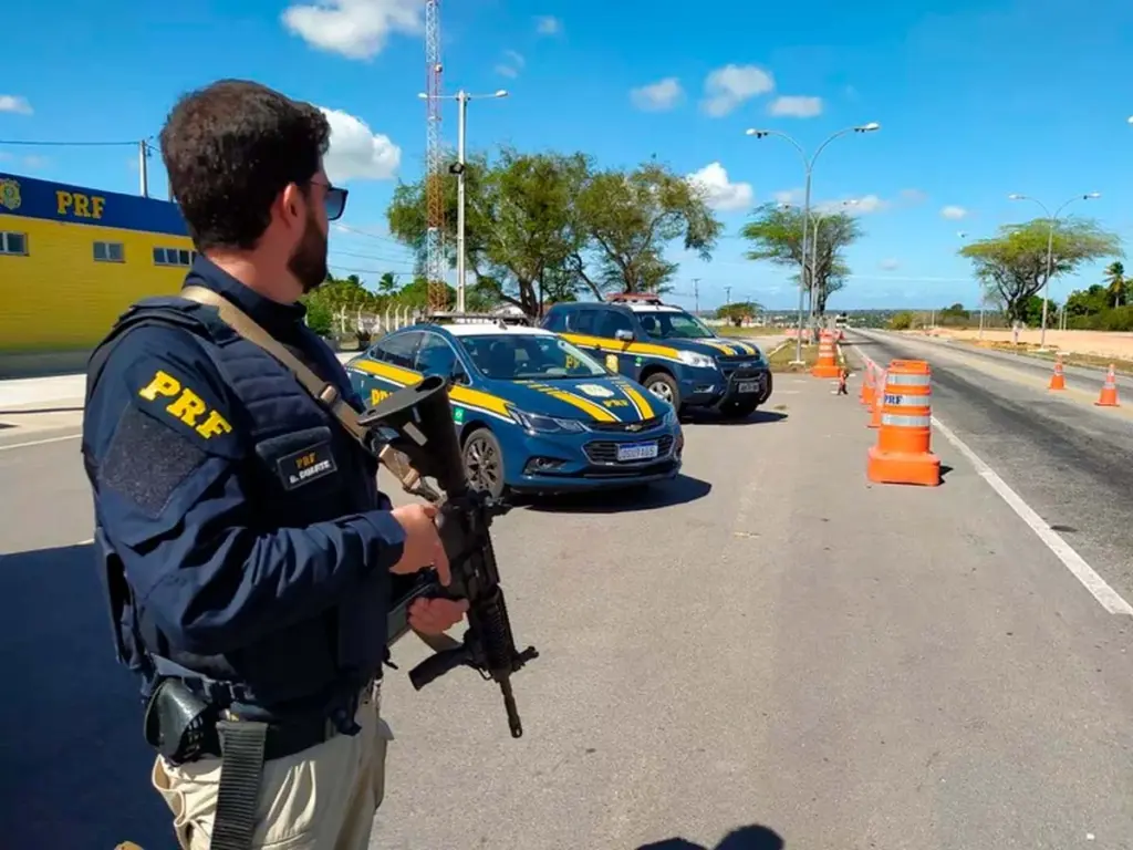 Polícial com uniforme em frente a carros da coorporação / Concurso PRF